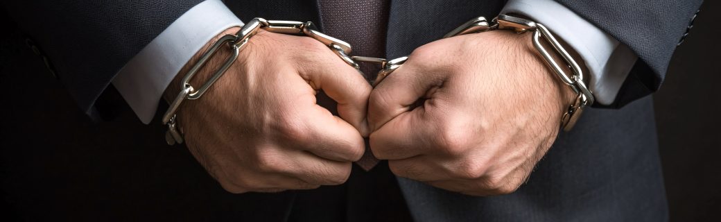 Businessman wearing handcuffs squeezing his hands together