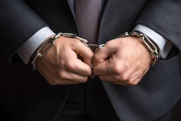 Businessman wearing handcuffs squeezing his hands together